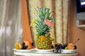 Pineapple,red apples,pears and blue grapes on the plates