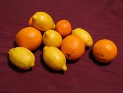 fresh oranges and lemon on purple fabric