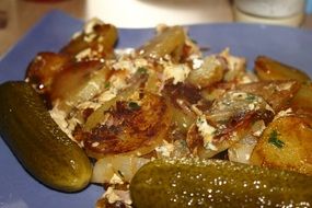 fried potatoes and pickled gherkin close-up