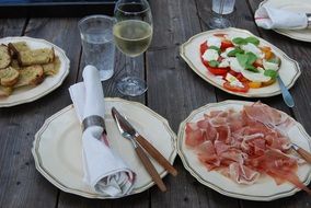 sliced meat and vegetables on wooden table, outdoor party