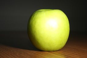 one green apple on the table in light