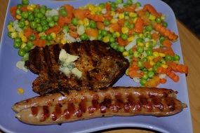 Grilled sausage with vegetables on a blue plate