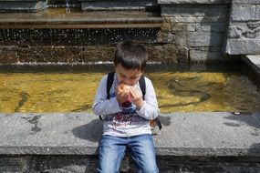 boy eating apples near water