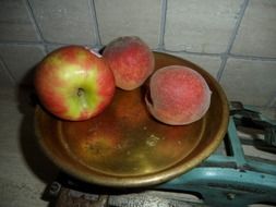 apple and two peaches on scales