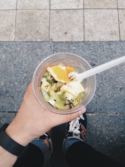 fruit salad in cup in personâs hand outdoor