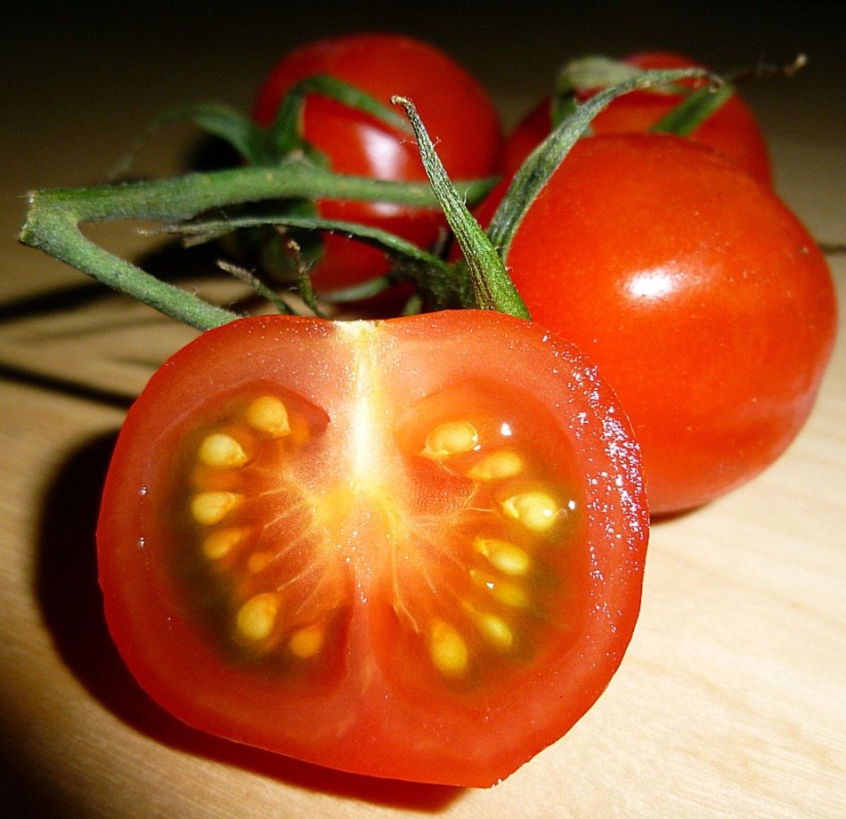 tomatoes on a green branch on a cutting board close up
