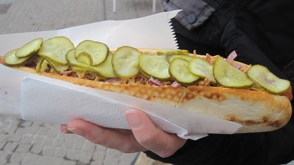 big sandwich with cucumber in hand close-up