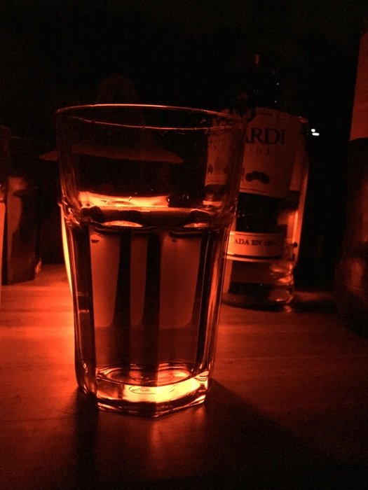 glasses with drink in dark red lighting
