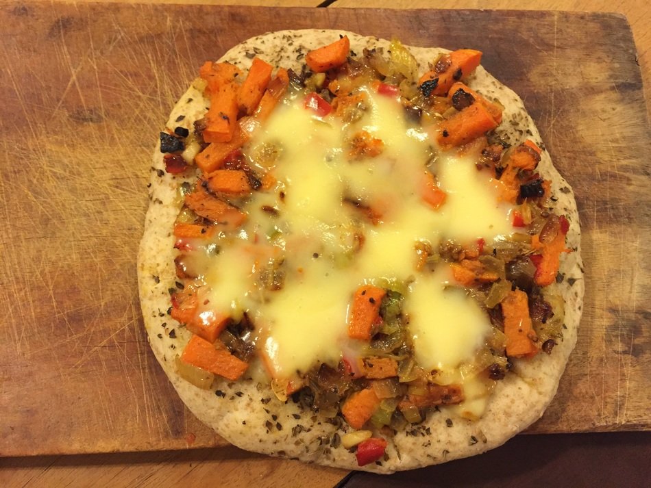 pizza with vegetables on a wooden cutting board
