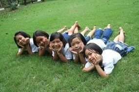 girls lie on the green grass