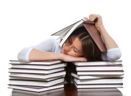 girl is sleeping on a stack of books