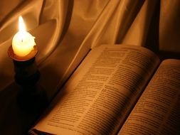 candle beside of open Bible
