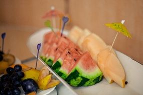 sliced pears, watermelon, grapes and banana on a buffet