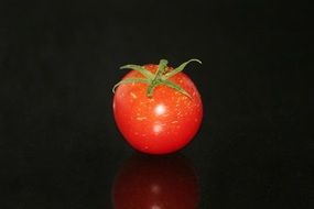 red tomato with green tail on a black background