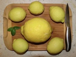 six yellow lemons on a cutting board