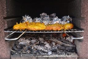 bbq chicken on grill above charcoal
