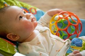baby lying on the bed with a toy