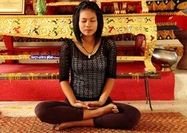 young thai woman meditating in a buddhist temple