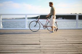 man holding a bicycle on a pier