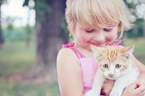 cute baby girl holding a white kitten