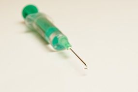 green syringe on white table