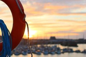 life belt on a beach cost with many boats behind