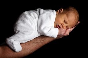 newborn baby on male hand