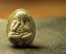 tiny carved image of a medettating monk in a stone