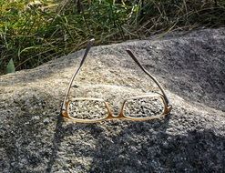 glasses upside down on a rock near grass