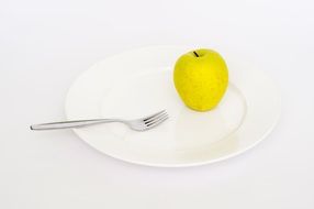 yellow apple and fork on plate