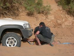 two men preparing car for towing in desert