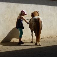 little girl stands near the horse