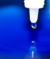 drop with plastic pipette reflected on a blue surface