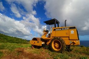 yellow crawler tractor on a green field