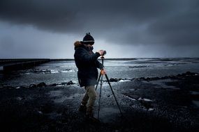 photographer with a camera on a tripod during bad weather