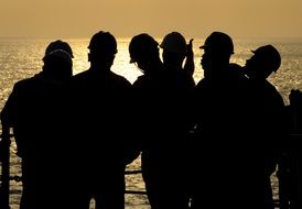 silhouettes of men working at sunset