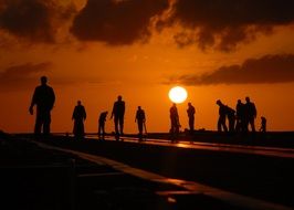 silhouettes of people on the beach at sunset