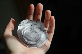 paper flower from music sheet on female hand