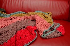 colorful crochet blanket on red sofa