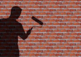 shadow of a painter against a brick wall