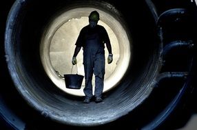 worker with a bucket in a concrete tunnel