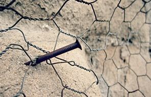 wire net on rusty nail at wall