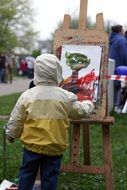 child boy painting bright figure in park