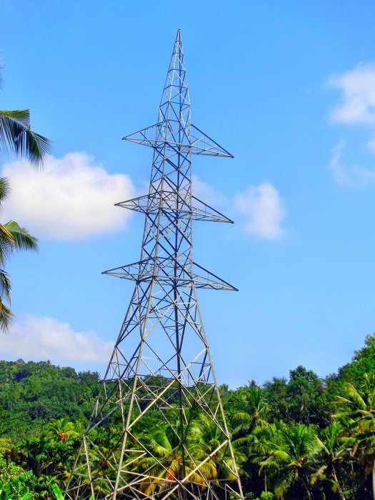 electrical tower at sky in front of forest