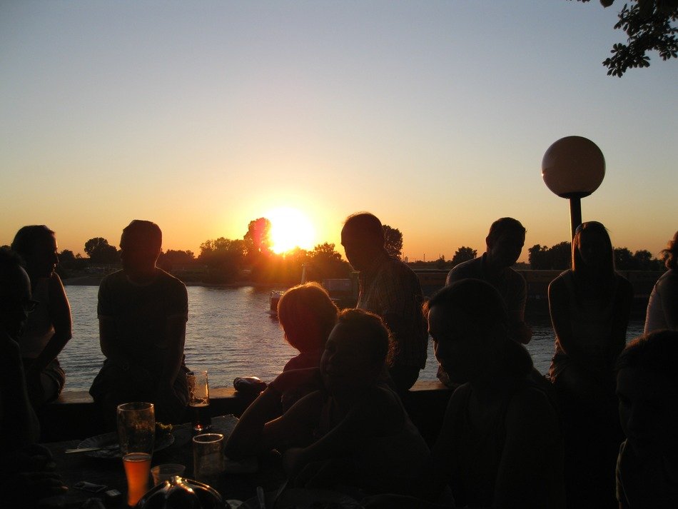 people relax and drink beer on sunset background on the river Rhine