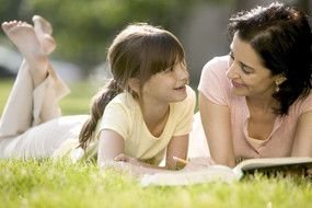 Mom and daughter are lying on the grass