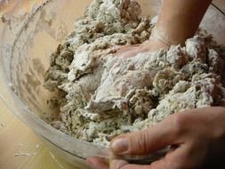 baker kneads dough on bread with his hands