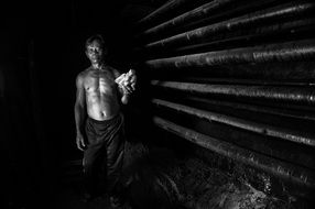 Black and white photo of a worker in a dark room