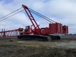 worker at cabin of red crane on tracks