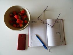 strawberries and notebook on a table